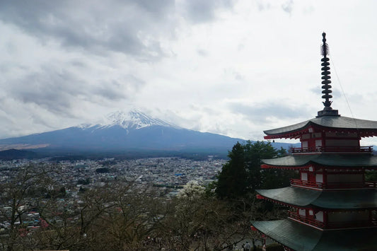Blick von der Chureito Pagode auf den Mount Fuji in Japan, mit der roten Pagode im rechten Vordergrund und der Stadt Fujiyoshida darunter.