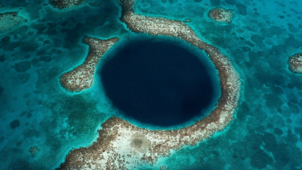 Das kreisrunde Great Blue Hole im türkisen Meer vor Belize aus der Luft.