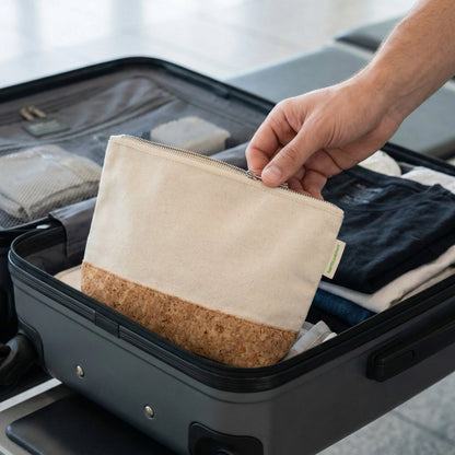 Nachhaltig reisen: Eine Hand legt den plastikfreien Kulturbeutel aus Kork und Baumwolle von Bamboovement in einen gepackten Koffer.