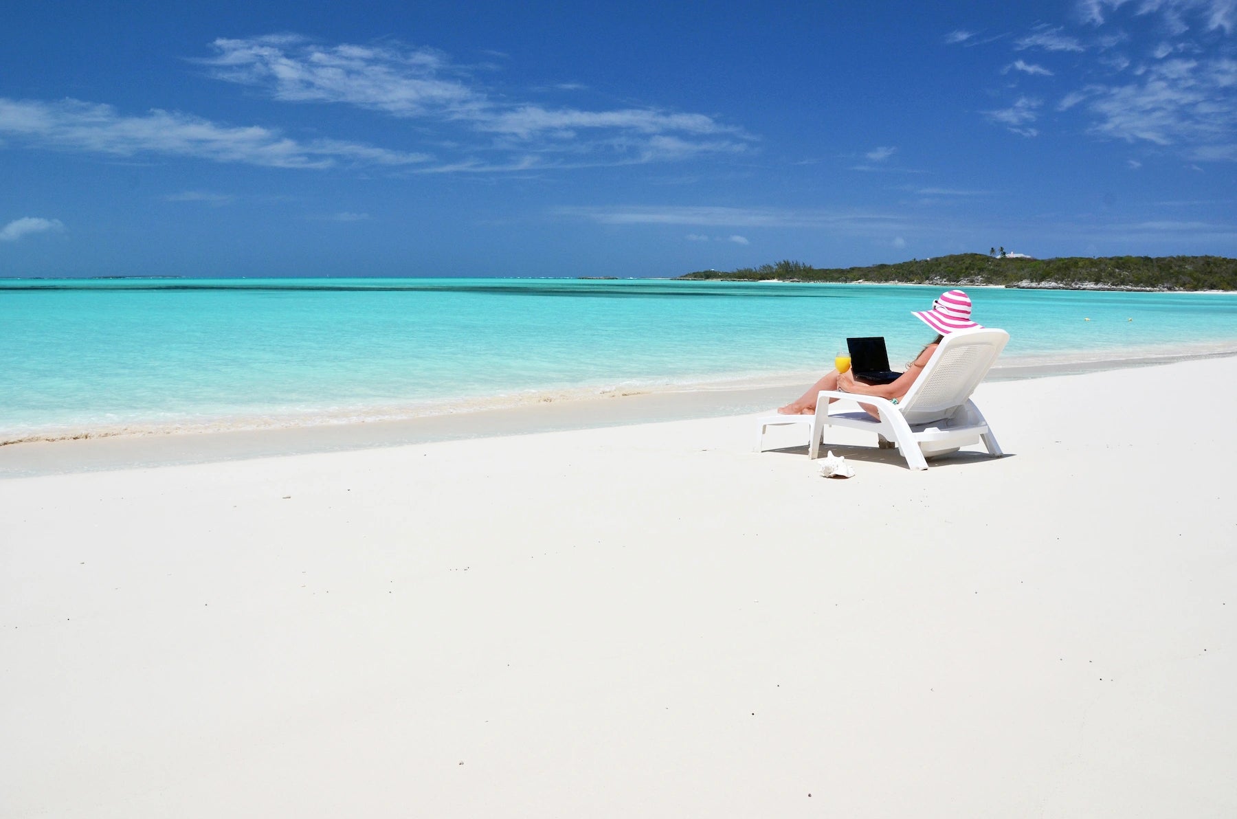 Türkisfarbene Lagune mit weißem Sandstrand und Palmen auf den Bahamas.