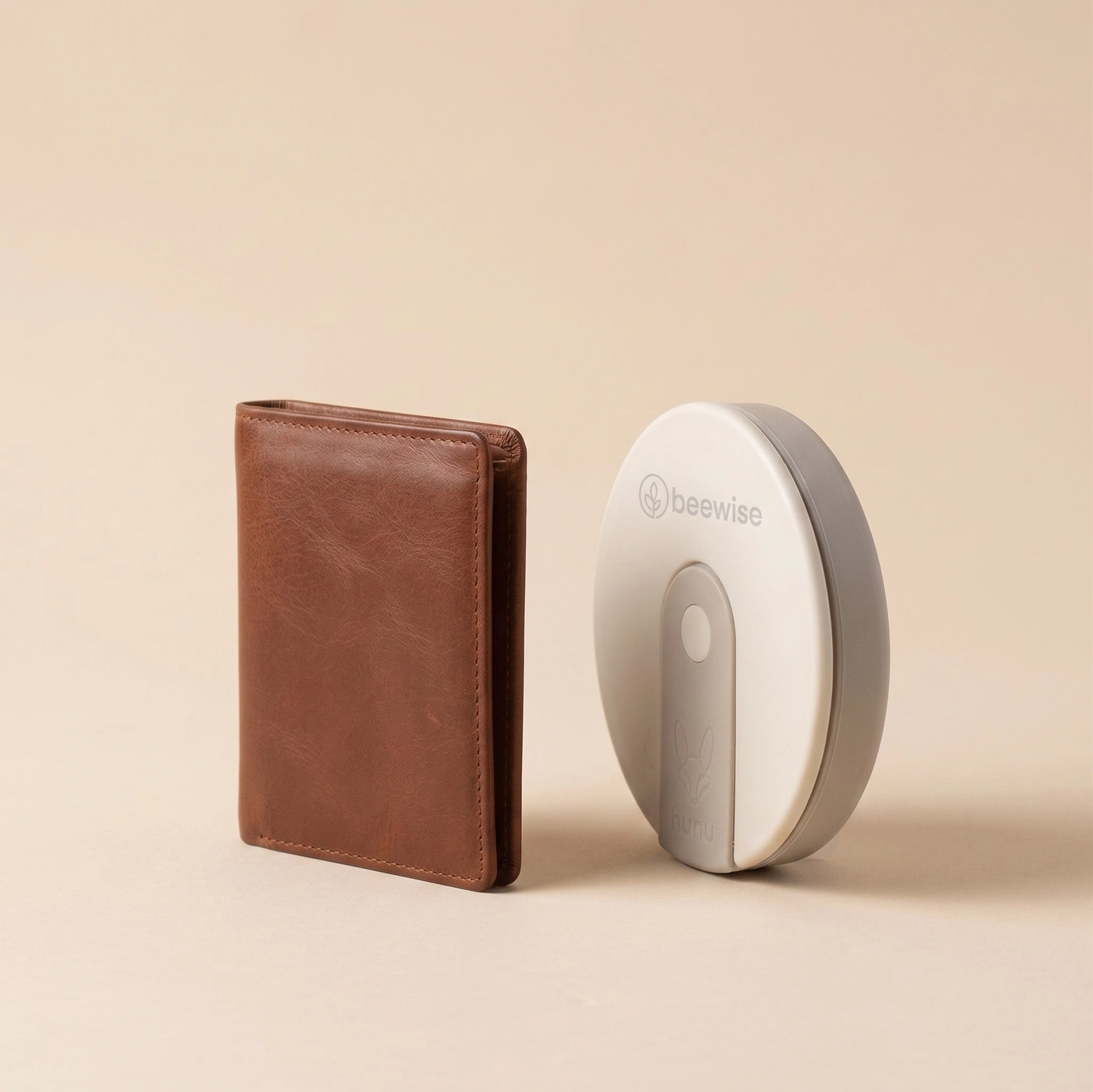 A brown leather wallet stands next to a white and gray BeeWise Hunu travel cup.