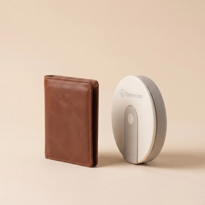 A brown leather wallet stands next to a white and gray BeeWise Hunu travel cup.