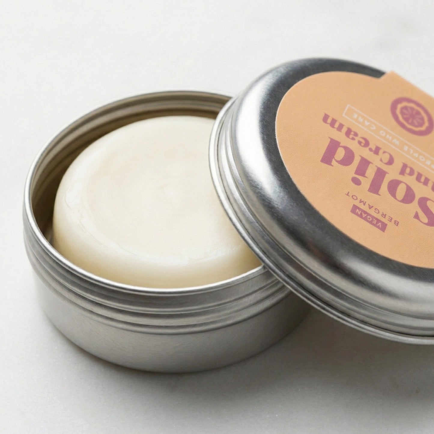 Nahaufnahme der geöffneten Metalldose mit der festen, cremeweißen Handcreme Bergamotte – plastikfreie Pflege für trockene Hände auf Reisen.
