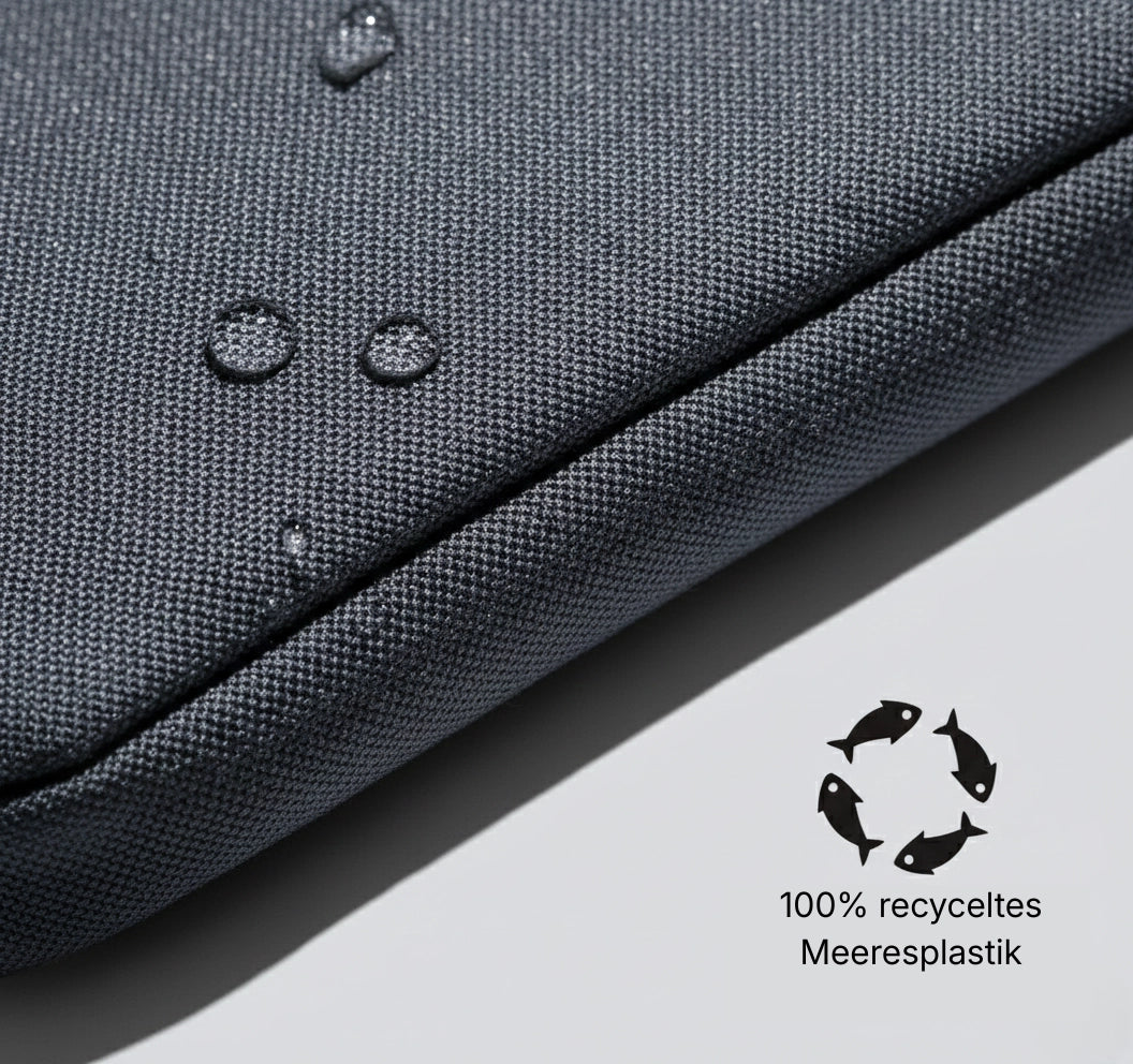 Nahaufnahme des wasserabweisenden, grauen Gewebes der Tre Karo Umhängetasche aus 100% recyceltem Meeresplastik mit Wassertropfen auf der Oberfläche.