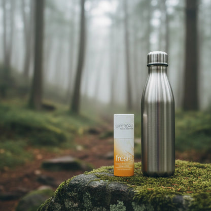 Der aluminiumfreie Deostick 'fresh!' steht zusammen mit einer Edelstahl-Trinkflasche auf einem moosigen Stein in einem nebligen Wald – ideal für Outdoor-Aktivitäten.