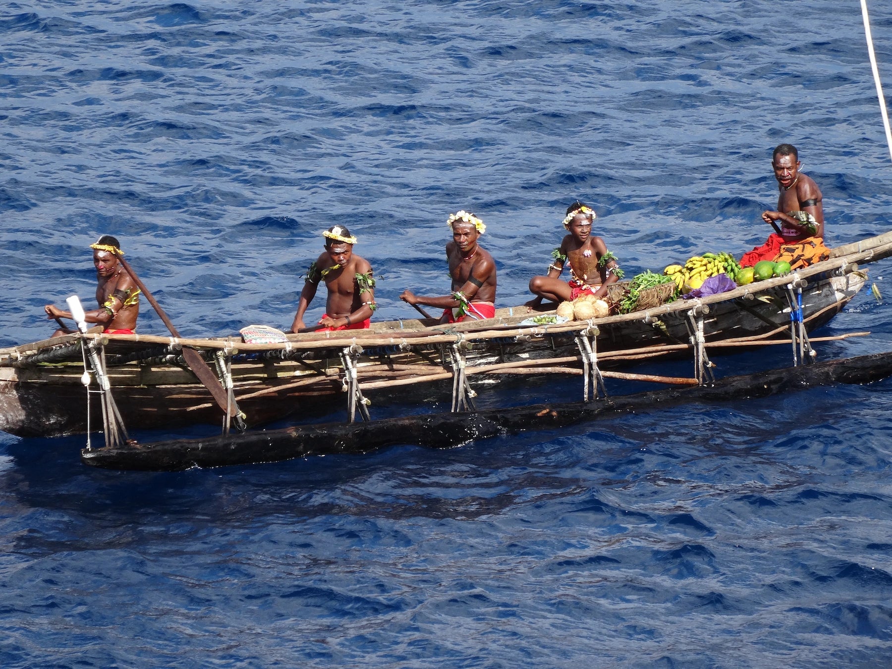 Ein Kanu auf dem Wasser mit 5 Einheimischen in Papua Neuguinea.