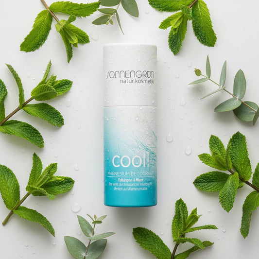 Nachhaltiger Magnesium-Deostick 'cool!' von Sonnengrün mit Eukalyptus und Minze, flach liegend zwischen frischen Minzblättern und Wassertropfen.