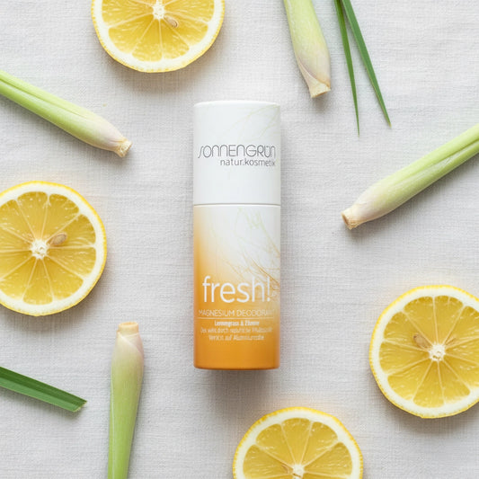 Nachhaltiger Magnesium-Deostick 'fresh!' von Sonnengrün mit Lemongrass und Zitrone, umgeben von frischen Zitronenscheiben und Zitronengras auf hellem Stoff.