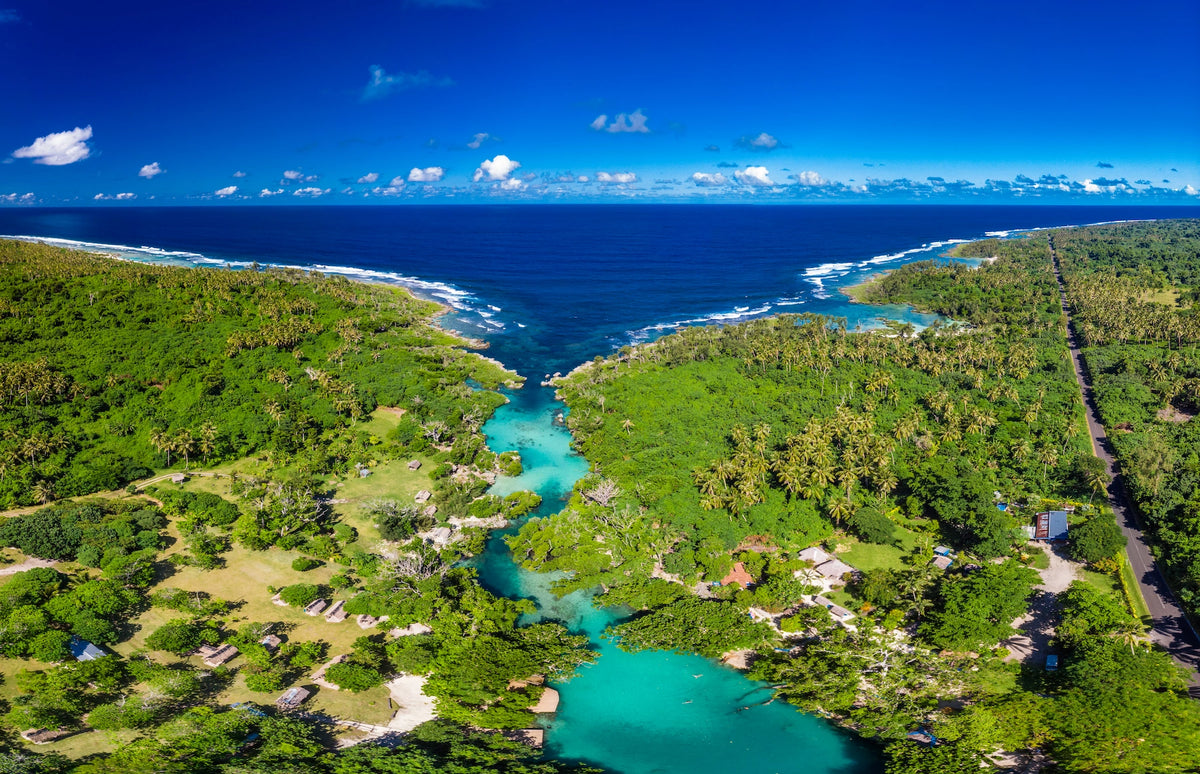 Drohnenaufnahme der Blauen Lagune auf Vanuatu, deren leuchtend türkisblaues Wasser sich durch dichten, grünen Dschungel bis zum tiefblauen Ozean schlängelt.