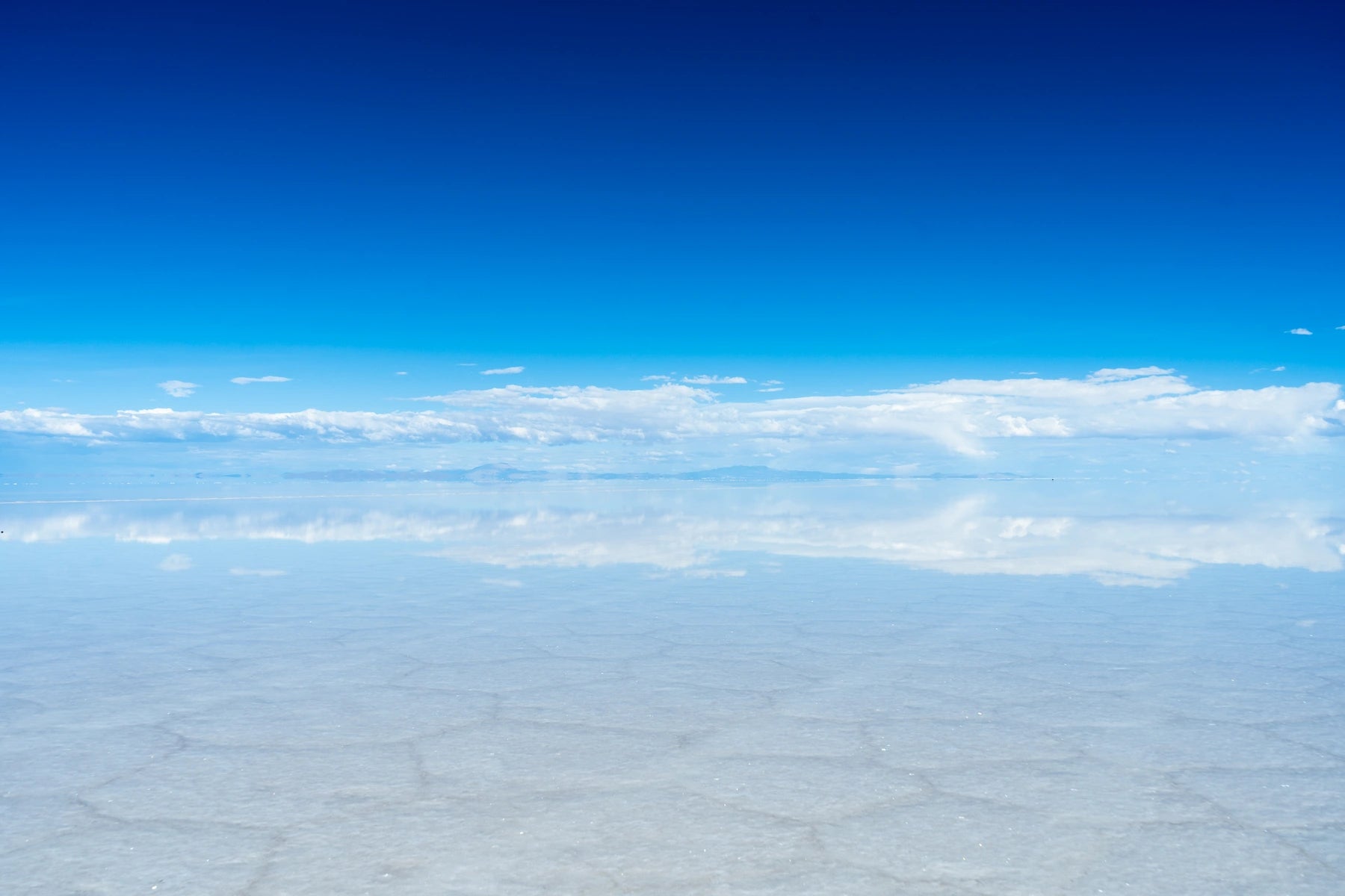Spiegelnder Salar de Uyuni mit weitem Himmel in Bolivien.