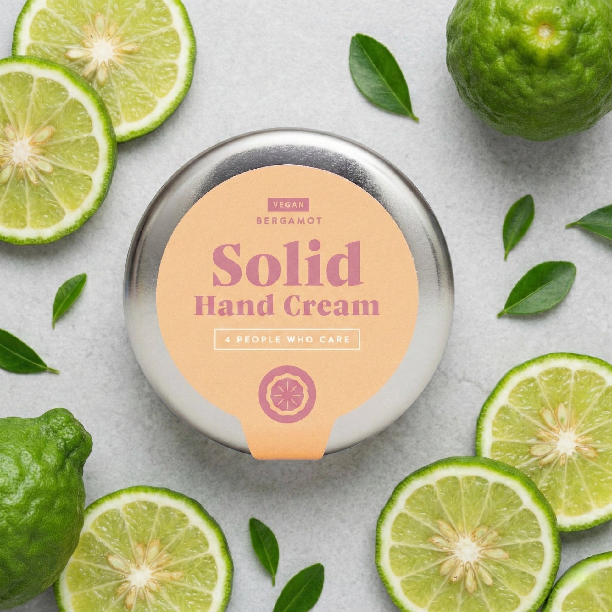 Draufsicht auf die feste Handcreme Bergamotte von 4PEOPLEWHOCARE, umgeben von frischen Bergamotte-Scheiben und grünen Blättern auf hellem Untergrund.