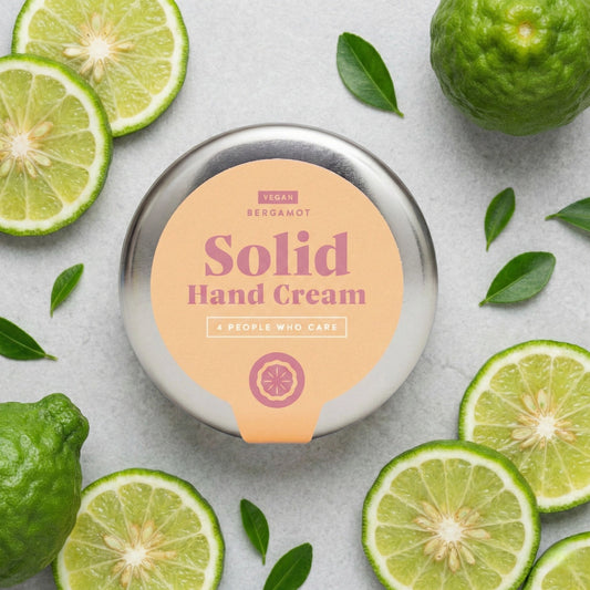 Draufsicht auf die feste Handcreme Bergamotte von 4PEOPLEWHOCARE, umgeben von frischen Bergamotte-Scheiben und grünen Blättern auf hellem Untergrund.